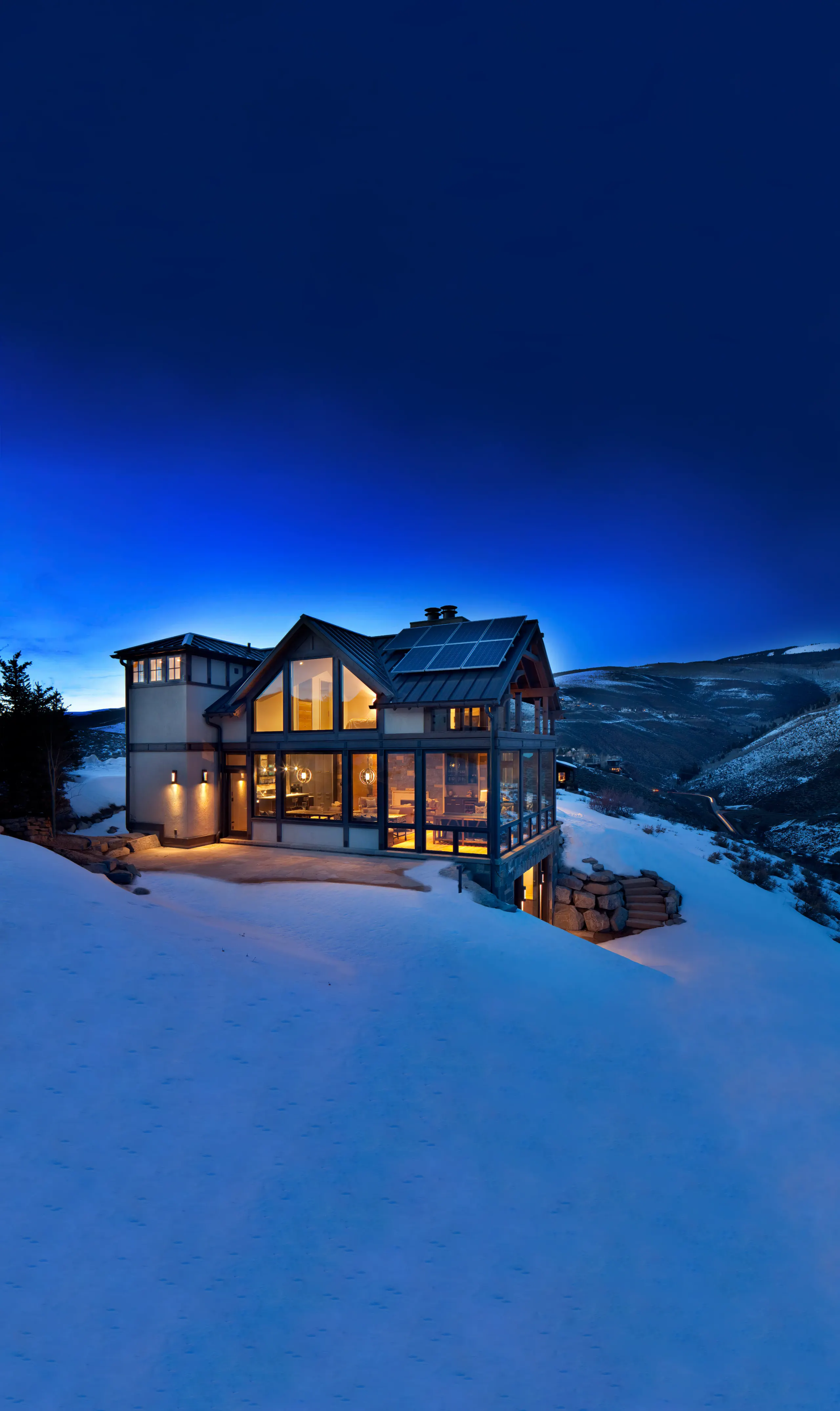 Smart home lit up at night in the snowy mountains